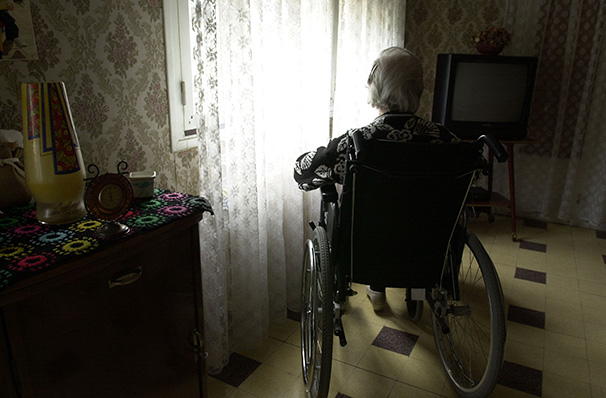 Elderly man in a wheel chair looks out the window.